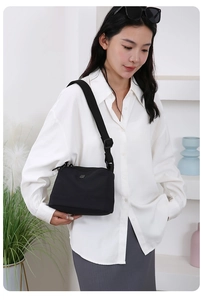 Gros plan d'un petit sac bandoulière en nylon noir porté avec une sangle décontractée