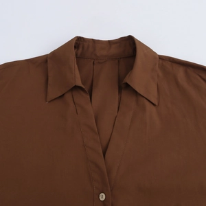 Close-up of brown poplin shirt featuring a V-neckline with lapel and a single button detail