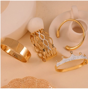 Close-up of four gold-plated titanium steel bracelets with crown and braided textures