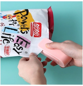 Tragbares Mini-Heißsiegelgerät in Rosa versiegelt Plastiktüte vor blauem Hintergrund