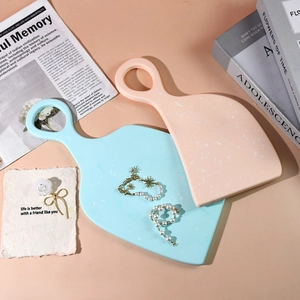 Macro detail of terrazzo style resin coaster trays in pink and blue with paddle handle