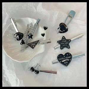 Detail of cute silver and black drip oil hair clips with star and heart designs