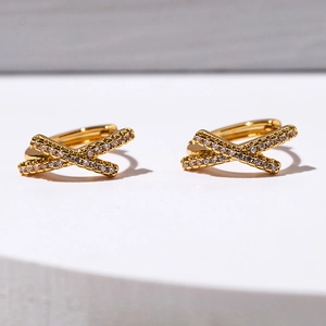 Detail of gold-plated X-shape huggie earrings featuring micro-paved sparkling cubic zirconia