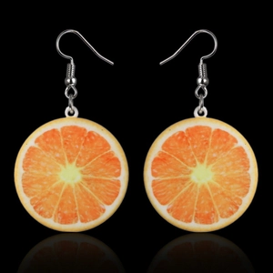 Close-up of creative orange slice earrings with metal hooks on a black reflective background