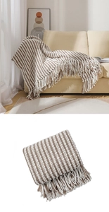 Detail of chunky knit throw blanket with brown and beige stripes and fringe tassels