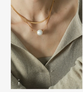 Close-up of double-layer gold necklace with a large white pearl on a woman's neck