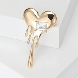 Detail view of a molten gold heart brooch with a large rectangular crystal stone