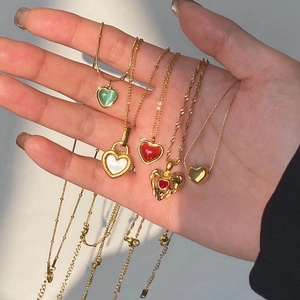 Detailed close-up of five assorted heart pendant necklaces in gold stainless steel