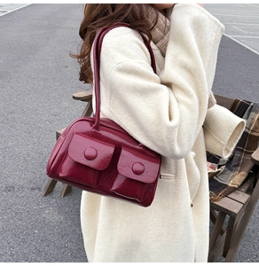 Detail of burgundy patent leather shoulder bag with vintage buckles and large pockets