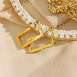 Detail view of gold rectangle hoop earrings featuring side-set sparkling zircon accents