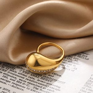 Detailed view of a gold teardrop ring with pavé zircon accents on a silk background