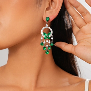 Detail of luxury drop earrings with green teardrop gemstones and silver tassels