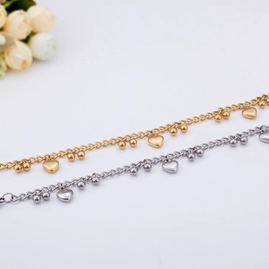Close-up of golden and silver titanium steel bracelets with heart and bead charms