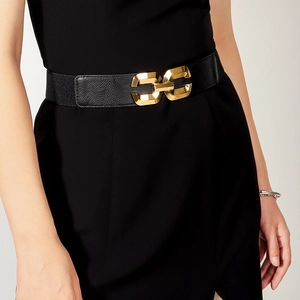 Women's black elastic waist belt with a stylish golden geometric buckle on a black dress