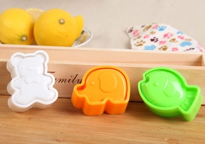 Detailed set of white bear, orange elephant, and green fish plastic rice molds on a wooden surface