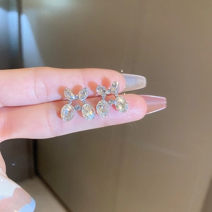 Close-up of elegant silver bow earrings with sparkling crystals worn on an earlobe