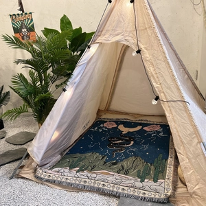 Detail of bohemian woven camping blanket with snake and moon patterns and tassel edges