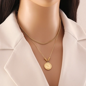 Close-up of golden double-layer necklace with vintage coin pendant and chunky chain