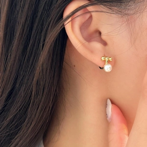 Close-up of elegant gold stud earring with a round white pearl on a female model