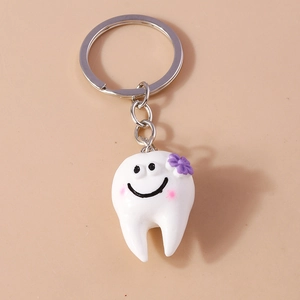Dettaglio ravvicinato di portachiavi a forma di dente in resina con piccolo fiore viola