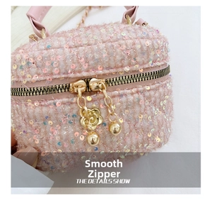 Close-up of pink sequined mini bag featuring smooth gold dual zippers and flower charms