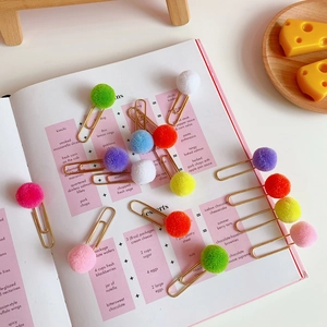 Creative colorful pom pom metal paperclips set on a recipe book for office and school supplies