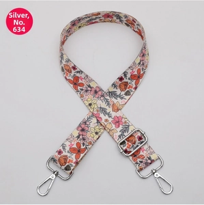 Detail of adjustable floral woven strap with silver spring hooks and metal buckle