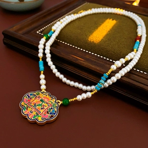 Macro shot of gold-plated Ruyi pendant with enamel floral patterns on pearl necklace