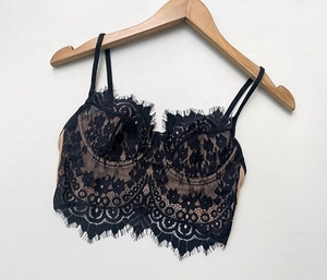 Close-up of black eyelash lace bralette with nude lining on a wooden hanger