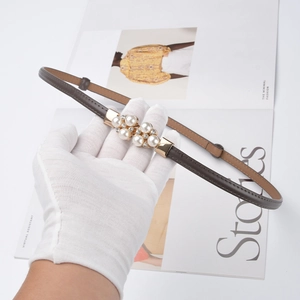 Brown leather women's belt featuring a gold pearl and rhinestone buckle on fashion magazine