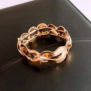 Detail of golden S-shaped elastic beaded bracelet with polished metallic finish