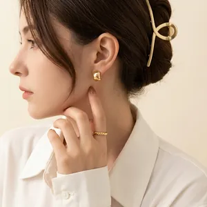 Elegant gold round stud earrings with matching ring and clip shown on a model