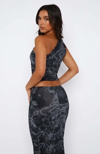 Detail of Y2K style one-shoulder crop top and matching long skirt in black printed fabric