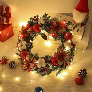 Couronne de Noël avec fleurs rouges, pommes de pin et lumières sur fond en peluche blanc