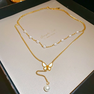 Dettaglio della collana multistrato dorata con farfalla, perle e intarsio di conchiglia