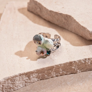 Close-up of irregular silver lava ring with colorful beads on beige stone surface