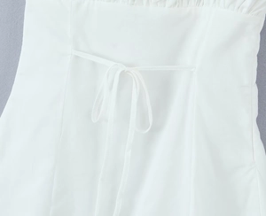 Close-up of a white lace-trimmed dress showing bow tie details and cotton fabric texture