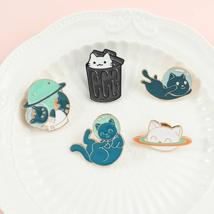 Detailed close-up of cute cartoon space cat enamel pins on a white decorative ceramic plate