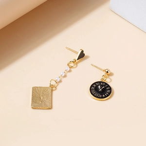 Detail of asymmetrical earrings with white pearls and a black clock face pendant