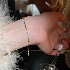 Detailed shot of a multi-color zircon tennis bracelet with a gold adjustable pull-chain
