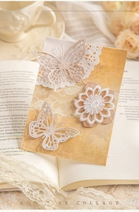 Detail of vintage collage kit with butterfly cutouts and lace paper on antique book