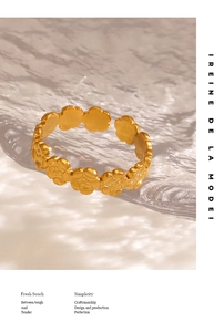 Artistic close-up of matte gold flower-shaped adjustable ring on water ripple glass