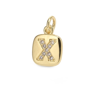 Macro detail of gold square pendant with letter X motif and sparkling zircon stones