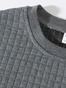 Detail of grey men's sweatshirt showing M-size tag and textured diamond pattern fabric