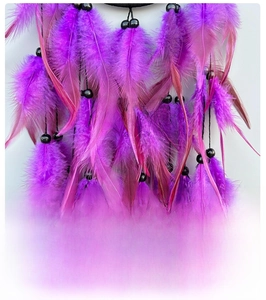 Macro view of natural purple and magenta feathers on a handmade dreamcatcher