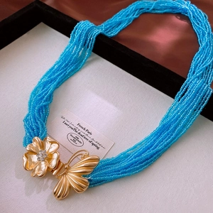 Détail de la boucle papillon dorée avec des couches de perles bleu ciel