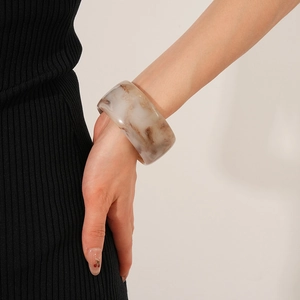 Macro detail of wide vintage resin bangle with brown marble texture on a model's wrist