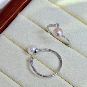 Close-up of white and pink natural freshwater pearl rings in a cream jewelry box