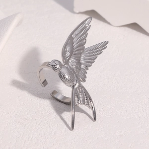 Détail d'une bague ouverte hirondelle argentée sur une surface en pierre minimaliste
