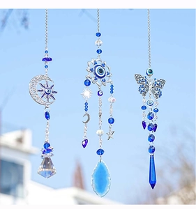 Close-up of blue evil eye butterfly suncatchers with crystal prisms against blue sky